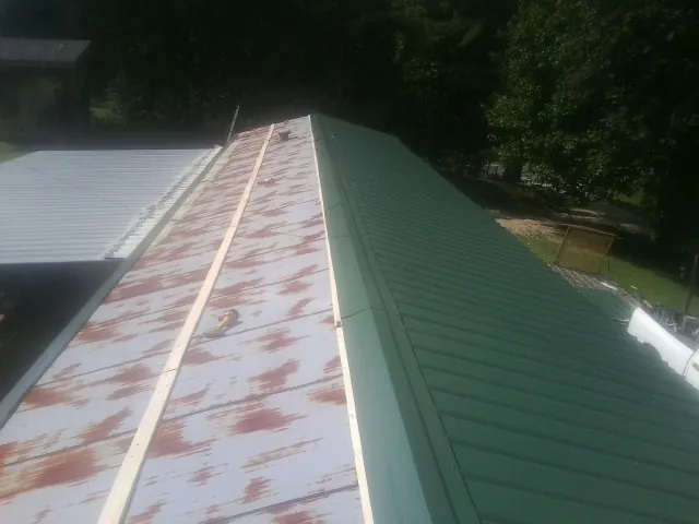 Old rusted panels beside newly installed green metal roofing — Wind Damage Roof Repair by Roofing Brothers in Poncha Springs