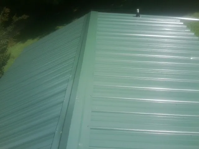 New green metal panels meeting at the ridge of a roof — Flat Roof Repair work by our crew in Poncha Springs