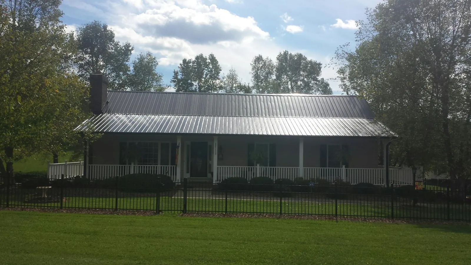 Gray metal roof on a brick ranch with a full width front porch — Gutter Guard Installation work by our crew in Poncha Springs