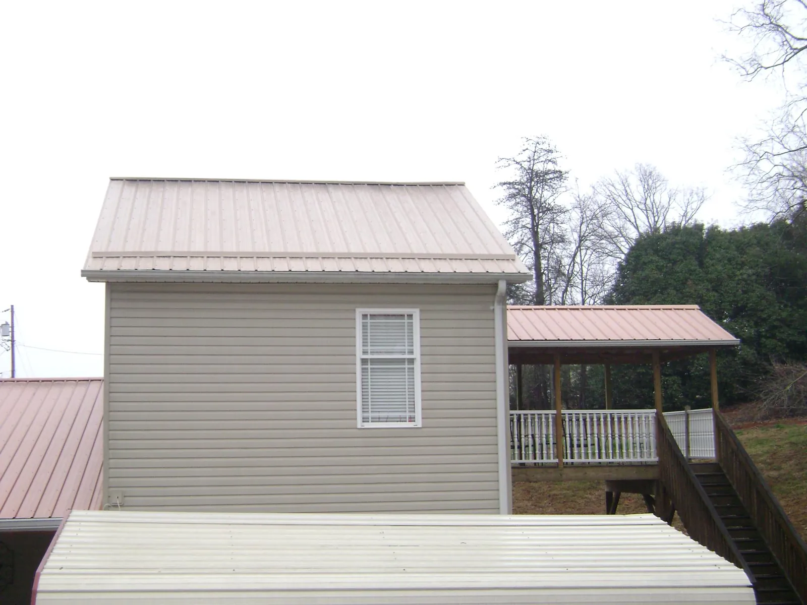 Tan metal roofs on a two story addition and attached porch, from a Roof Replacement job in Poncha Springs