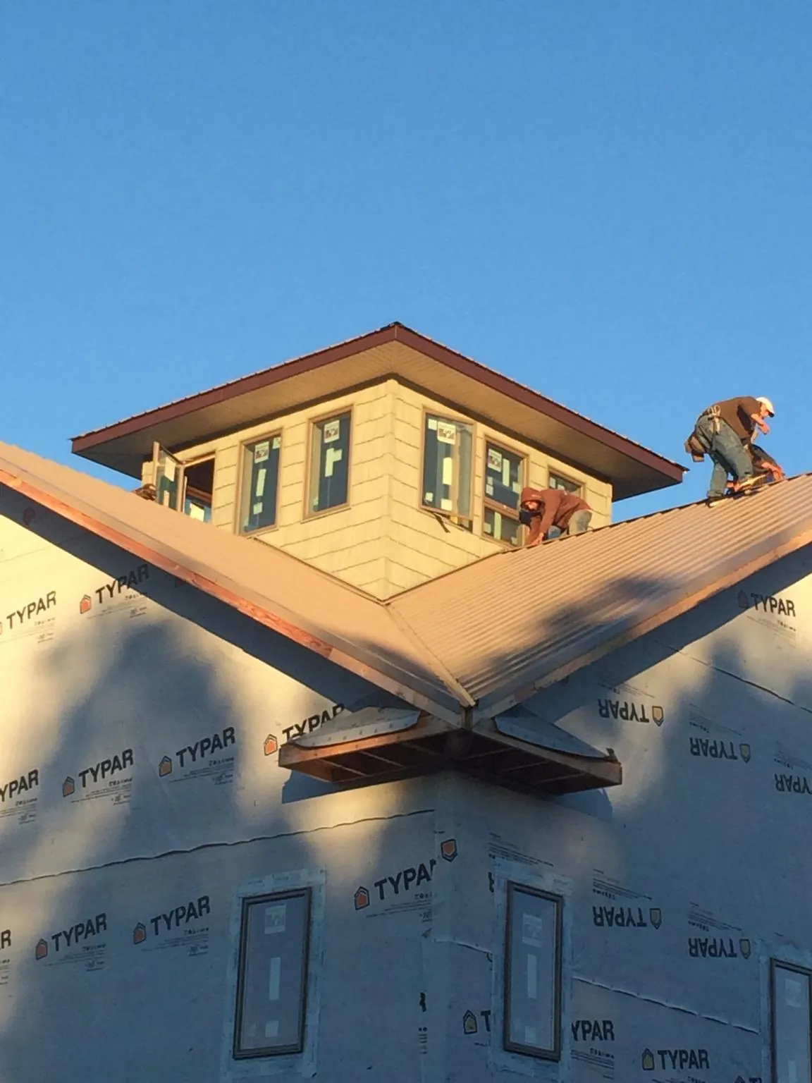 Roofers working around a rooftop cupola on a new metal roof at sunset — Roof Waterproofing in Poncha Springs by Roofing Brothers